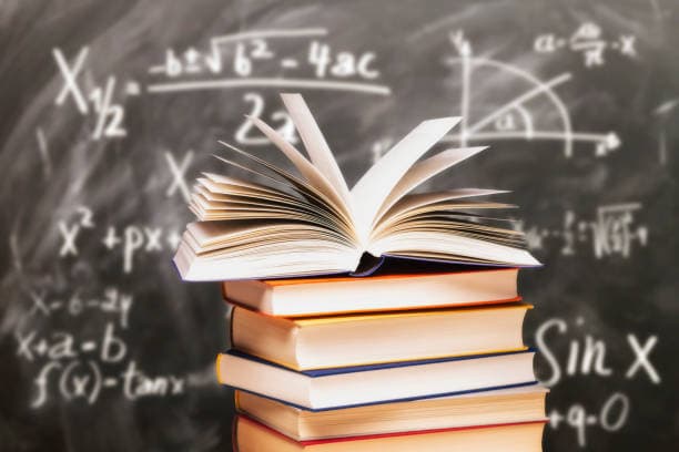 Stack of books in front of a black board
