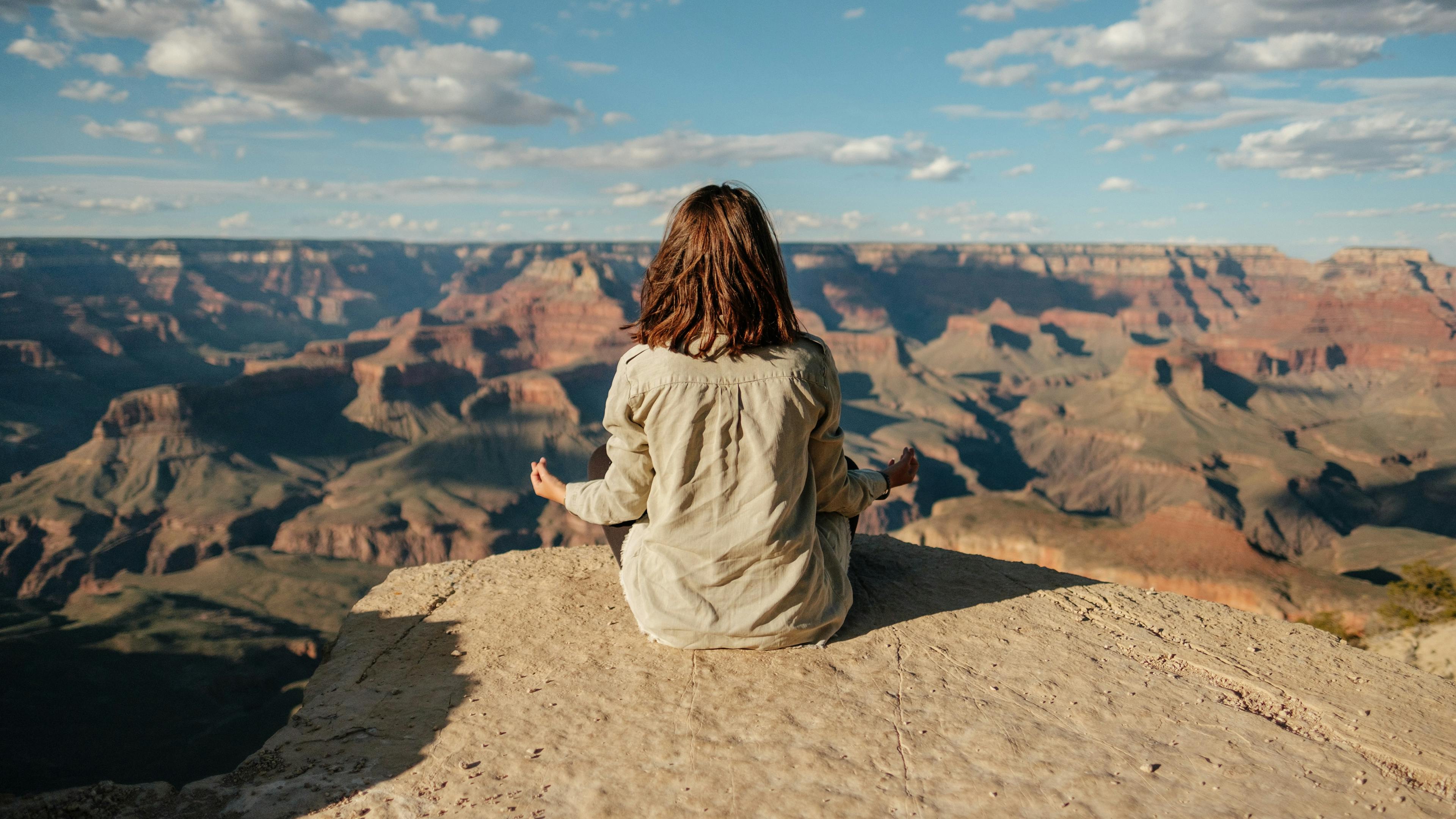 Woman meditating in front of a scenic background